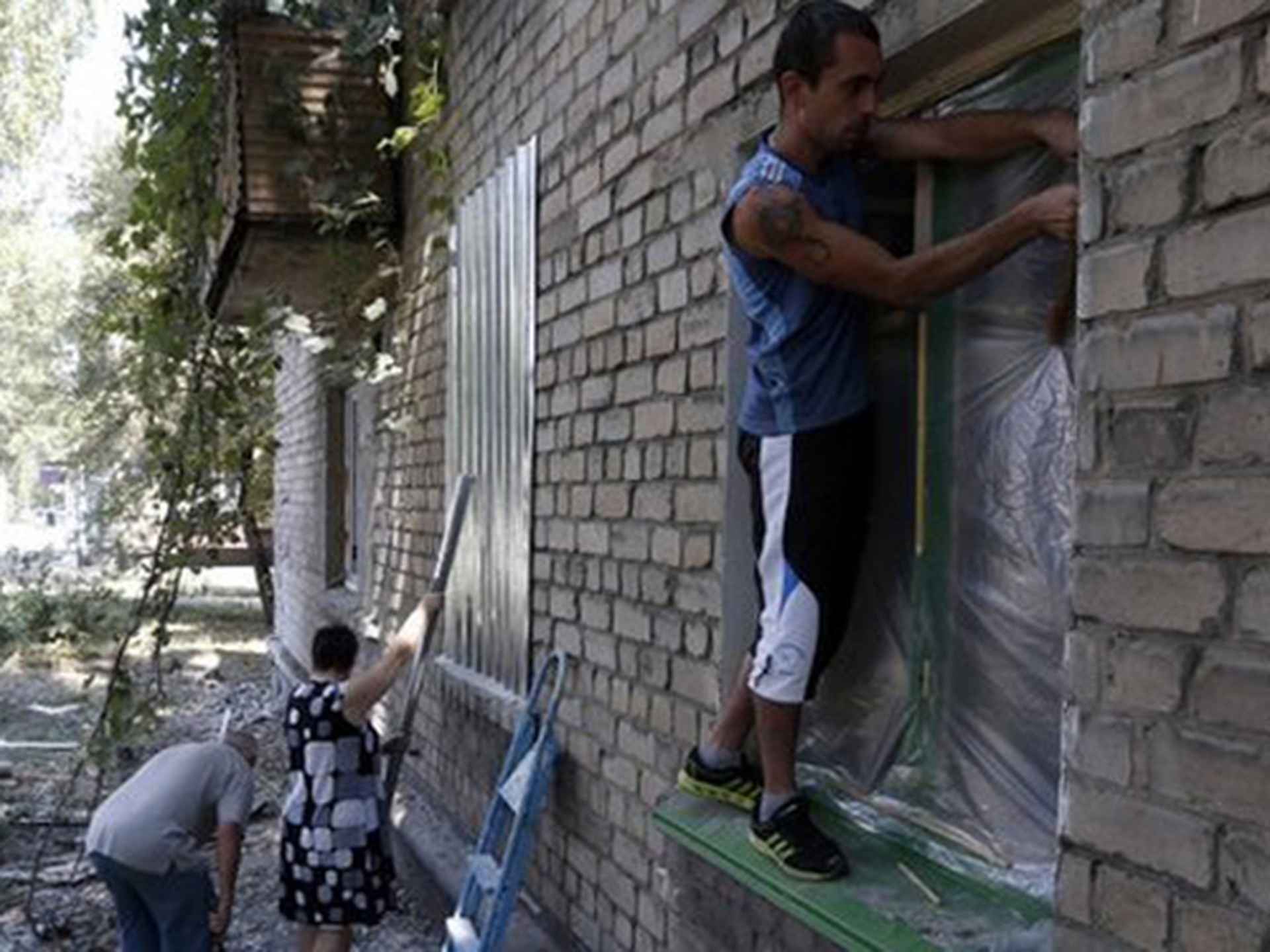 Người d&acirc;n tại Dontesk sửa chữa nh&agrave; cửa bị hư hại do giao tranh giữa qu&acirc;n ch&iacute;nh phủ v&agrave; phe ly khai
Ảnh: Reuters