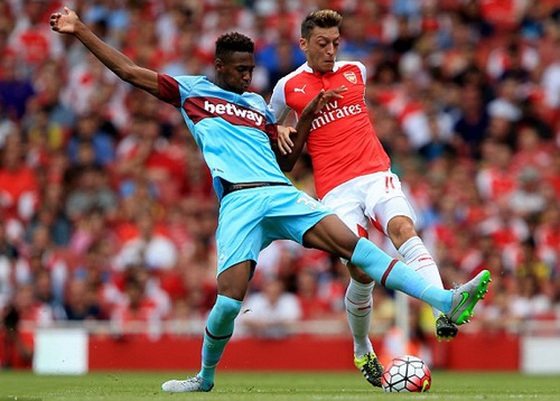 Ozil (phải) bị cậu b&eacute; Oxford đeo b&aacute;m chặt