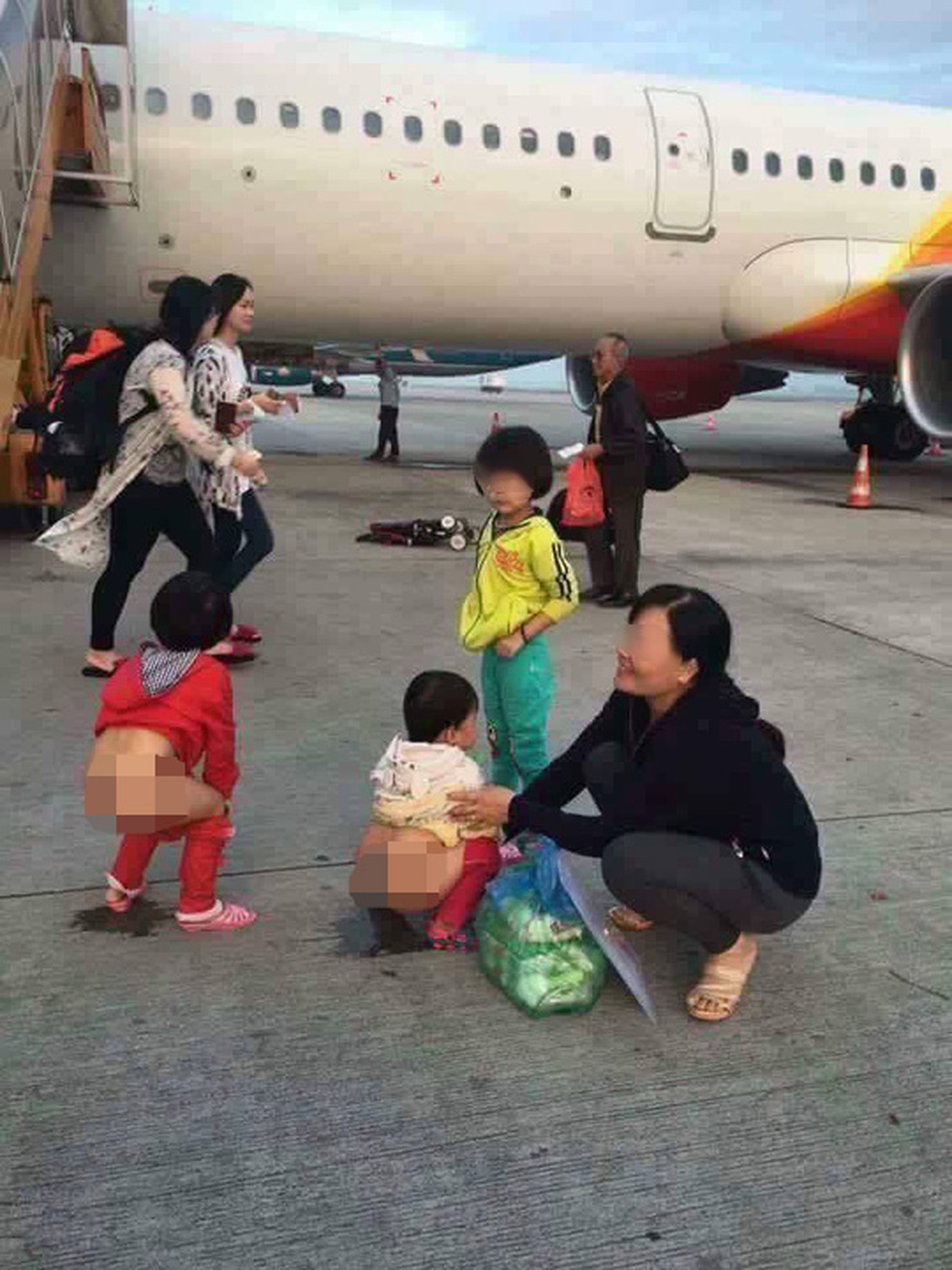 Người phụ nữ tươi cười cho những đứa trẻ t&egrave; bậy cạnh m&aacute;y bay - Ảnh: Facebook