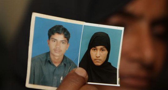Một phụ nữ Pakistan cho xem hình con trai bà là Sajjad Ahmed và vợ Muafia Bibi bị gia đình cô gái giết chết hôm 27-6. Ảnh: AP