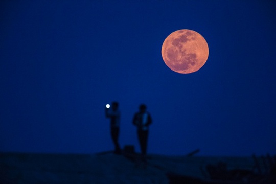 Người đàn ông đang chụp ảnh trăng máu ở khu vực ngoại ô Thượng Hải - Trung Quốc. Ảnh: Reuters
