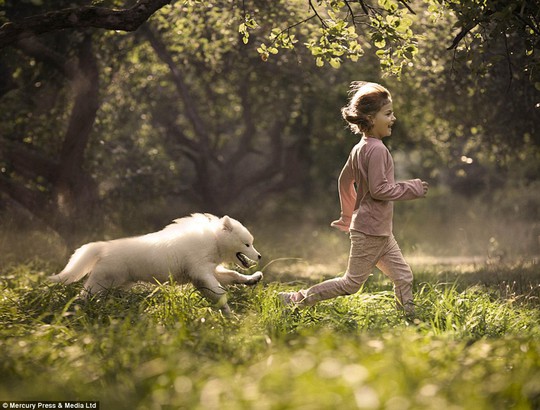 A young girl is chased by her dog as she charges through a woodland - the photographer said pets are members of our family 