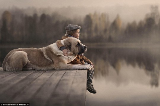 Photographer Elena Shumilova captures a young boy gazing out on to a lake with his arm wrapped around his pet dog 