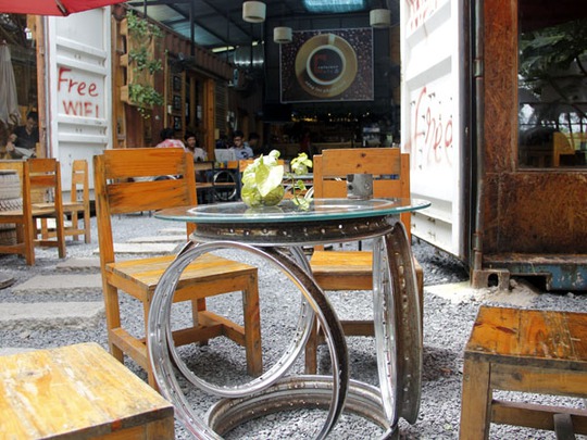 Cùng với bàn ghế gỗ thường thấy, Café Contaier còn tận dụng những phụ tùng bỏ đi của mô tô, xe hơi, xe tải như vỏ xe, mâm, sên cam, vòng bi, bạc đạn... làm thành những đồ trang trí nhằm gây ấn tượng cho khách, cũng như tạo phong cách bụi bậm của chủ nhân.