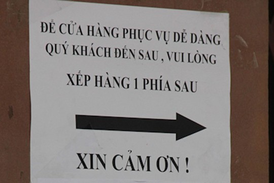 Biển nhắc nhở khách hàng xếp hàng chờ mua bánh được dán trước cửa hàng.