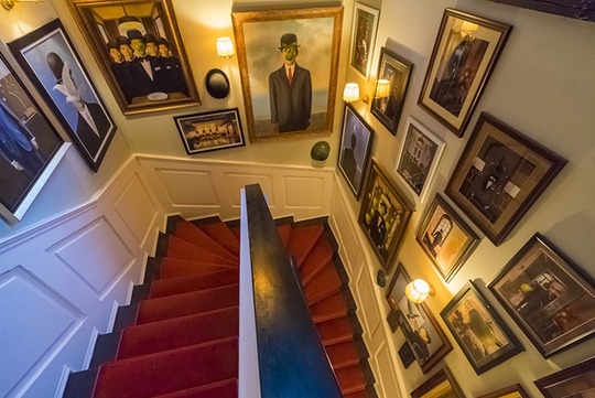 Lối cầu thang dẫn lên khu vực trên lầu được trang trí với các bức họa Thái Công theo phong cách Magritte tạo nên ấn tượng thị giác.