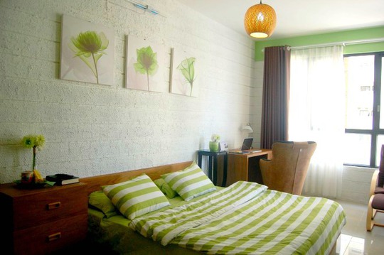 Bộ drap giường và những bức tranh treo tường được phối theo tông màu xanh lá chủ đạo. Màu trắng từ chiếc rèm cửa và tường phối theo phong cách nhẹ nhàng đem đến cảm giác thư giãn.