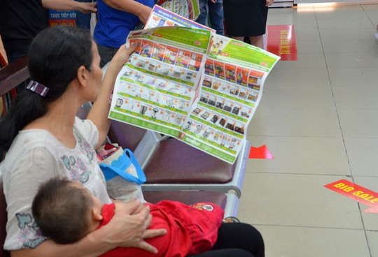 Một phụ nữ ôm con đến trung tâm để mua hàng giảm giá