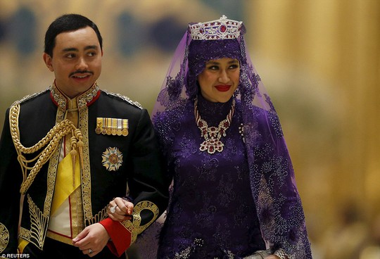 Chú rể mặc quân phục, cổ áo nạm kim cương trong khi cô dâu mặc bộ váy dài màu tím. Ảnh: Reuters