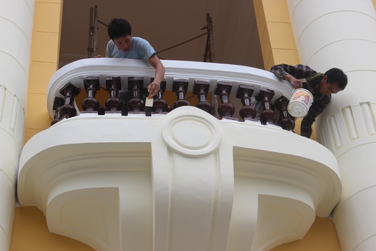 Thợ sơn đang sơn những lớp nhạt hơn đè lên lớp sơn vàng đậm trước ngôi nhà Thợ sơn đang sơn những lớp nhạt hơn đè lên lớp sơn vàng đậm trước ngôi nhà