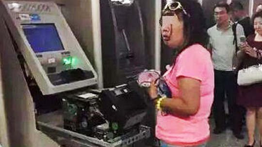 Người phụ nữ tay không tháo tung máy ATM. Ảnh: SCM