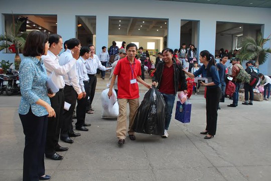 Ông Phạm Văn Hoa (giữa), Phó chủ tịch LĐLĐ quận Bình Thạnh hỗ trợ công nhân mang hành lý ra xe trước lúc khởi hành
