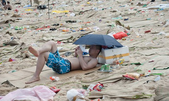 
Du khách đọc sách trên bãi biển toàn rác ở Trung Quốc. Ảnh: Barcroft Media
