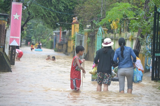 
Người dân hối hả chạy lũ trong khi trẻ em vui đùa trong nước lũ khá nguy hiểm
