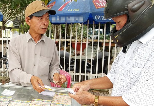 Ông Trần Hưng ở TP Trà Vinh (trái) tỏ ra dè dặt khi bán vé số điện toán in sẵn, vì địa phương này chưa được gắn thiết bị đầu cuối. Ảnh: Việt Tường.