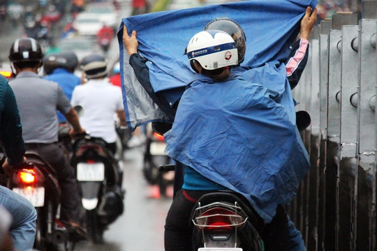 
Người đi xe máy dừng trên cầu vượt Hoàng Hoa Thám để mặc áo mưa, cản trở giao thông, góp phần khiến gia tăng ùn ứ.
