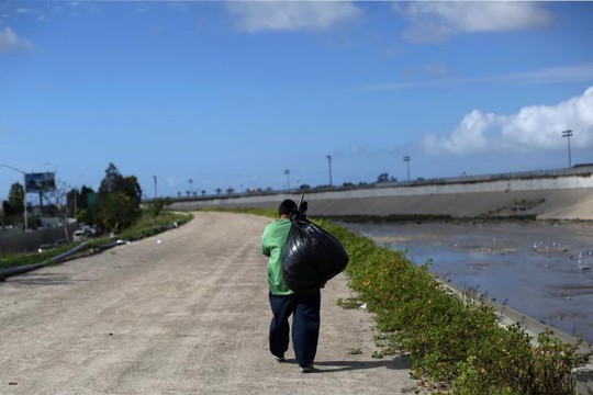 Một người Mexico bị trục xuất khỏi Mỹ khệ nệ vác đồ gần sông Tijuana, Mexico, ngày 22-2. Ảnh: REUTERS