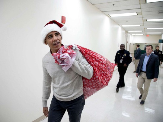 “Ông già Noel” Obama đội mũ đỏ, khệ nệ vác túi quà to - Ảnh 1.