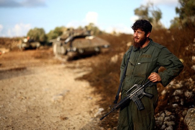 Một người lính Israel bên cạnh chiếc xe tăng của quân đội Israel gần biên giới với Lebanon. Ảnh: Reuters