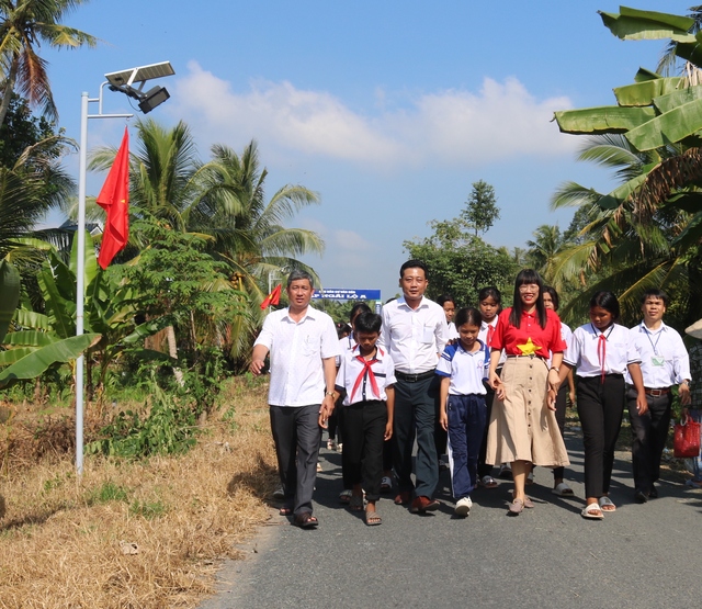 Các đại biểu cùng học sinh được Báo Người Lao Động hỗ trợ kinh phí học tập nối bước trên “Đường cờ Tổ quốc” tại xã Trà Côn, huyện Trà Ôn, tỉnh Vĩnh Long Ảnh: CA LINH