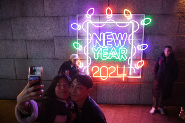 Một cặp đôi chụp ảnh selfie khi cùng nhau ra phố chào đón năm mới 2024 ở Seoul - Hàn Quốc - Ảnh: REUTERS