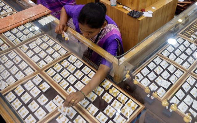 Một nhân viên bán hàng sắp xếp trang sức tại cửa hàng ở TP Mumbai - Ấn Độ  Ảnh: REUTERS