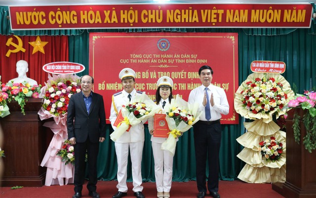 Hai tân Phó cục trưởng Cục Thi hành án dân sự tỉnh Bình Định (giữa) nhận quyết định bổ nhiệm và hoa tại buổi lễ