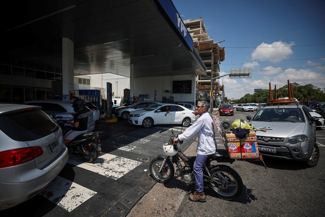 Người đi xe máy chờ đổ xăng ở Buenos Aires - Argentina ngày 8-12 giữa lúc các công ty dầu nước này đồng loạt tăng giá Ảnh: REUTERS