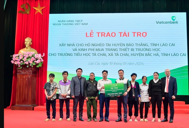 Ông Lê Hoàng Tùng - Phó Tổng Giám đốc Vietcombank (thứ 5 từ phải sang) trao biểu trưng hỗ trợ kinh phí xây dựng nhà cho 6 hộ gia đình khó khăn tỉnh Lào Cai