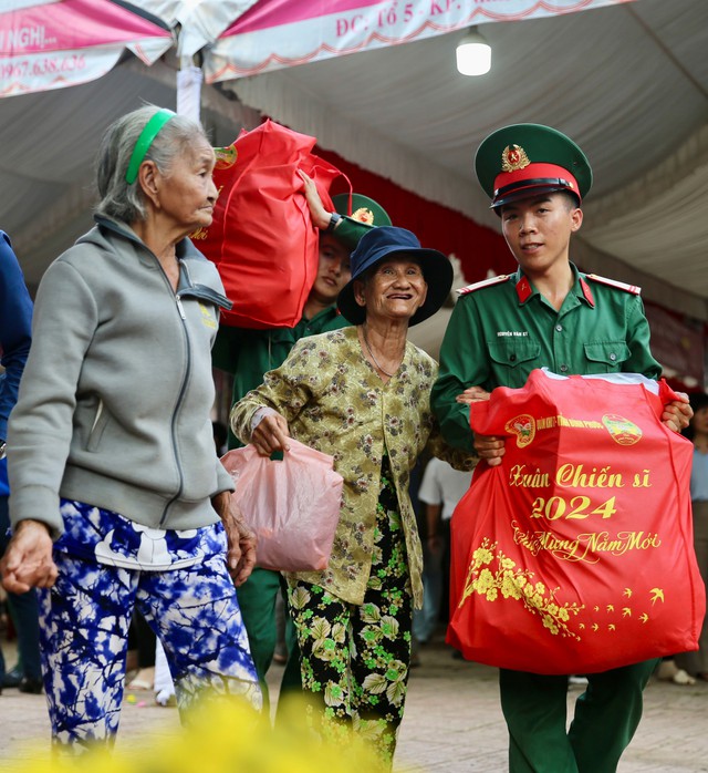 Chiến sĩ bộ đội biên phòng hỗ trợ 2 cụ già mang quà về nhà sau chương trình “Xuân ấm vùng biên” do Đảng ủy - Bộ Tư lệnh Quân khu 7 và Thường trực Tỉnh ủy, UBND tỉnh Bình Phước tổ chức Ảnh: HOÀNG TRIỀU