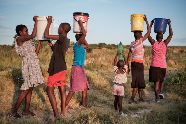 Cư dân thị trấn Pumula East ở Bulawayo - Zimbabwe trở về nhà sau khi lấy nước dùng từ giếng trong đợt nắng nóng và khô hạn đầu tháng 3-2024  Ảnh: REUTERS