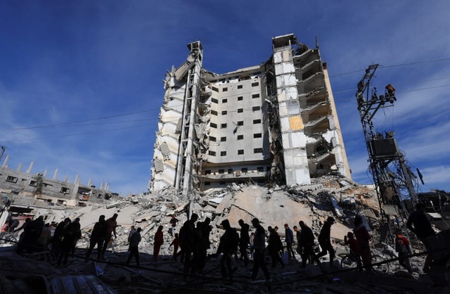 Người Palestine tụ tập gần một tòa nhà bị hư hại trong cuộc không kích của Israel ở Rafah, phía Nam Dải Gaza, vào ngày 9-3. Ảnh: Reuters