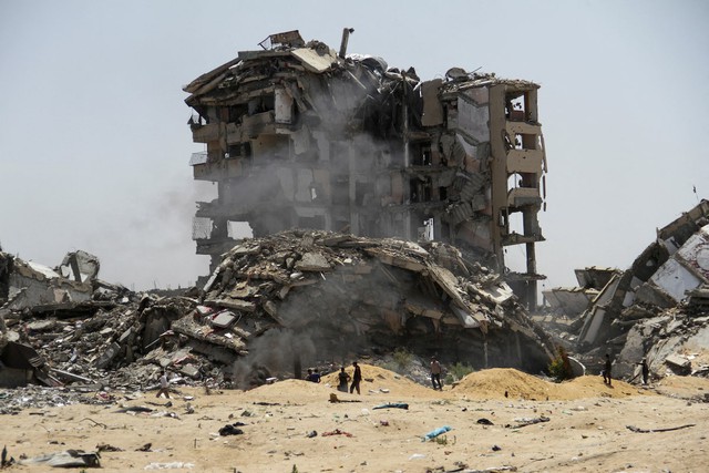 Người dân Palestine di chuyển qua các tòa nhà bị phá hủy bởi các cuộc tấn công của Israel ở Bắc Gaza. Ảnh: Reuters