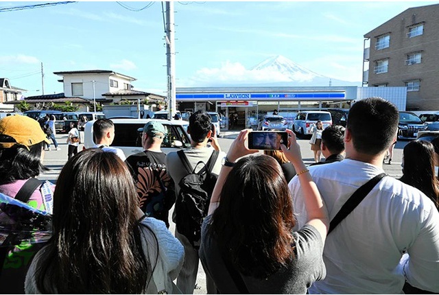 Du khách nước ngoài chụp ảnh núi Fuji từ vị trí phía trước cửa hàng tiện lợi Lawson ở thị trấn Fujikawaguchiko, tỉnh Yamanashi – Nhật Bản hôm 25-4 Ảnh: ASAHI