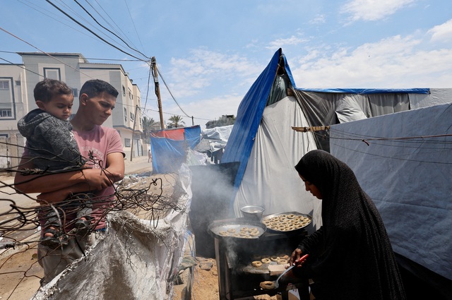 Một gia đình người Palestine làm các món bánh truyền thống cho lễ Eid al-Fitr, ngày lễ kết thúc tháng Ramadan, ở một khu lều trại tại Rafah hôm 8-4 Ảnh: REUTERS