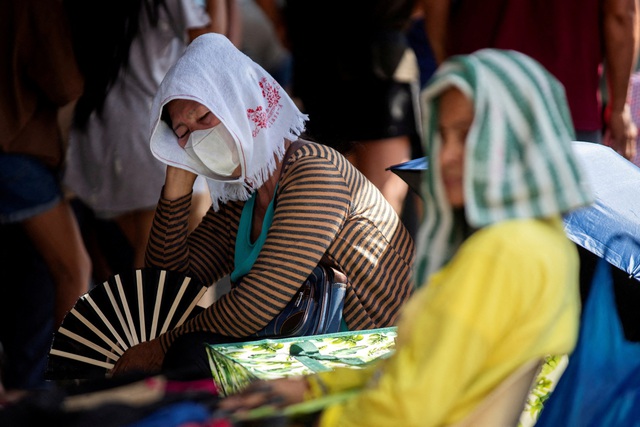 Những người bán hàng đội khăn, quạt chống nóng trong một khu chợ ở TP Manila - Philippines hôm 8-4 Ảnh: REUTERS