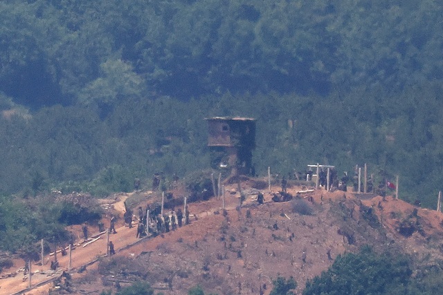 Người Triều Tiên thi công hàng rào quân sự gần chốt gác ở biên giới với Hàn Quốc (đoạn ở TP Paju  ở Hàn Quốc) Ảnh: REUTERS