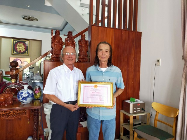 Ông Bùi Văn Hanh (phải) nhận bằng khen của UBND tỉnh Đồng Tháp do ông Lê Phương Thảo, Phó Chủ tịch Hội Chữ thập đỏ huyện Tam Nông, đến tận nhà trao tặng