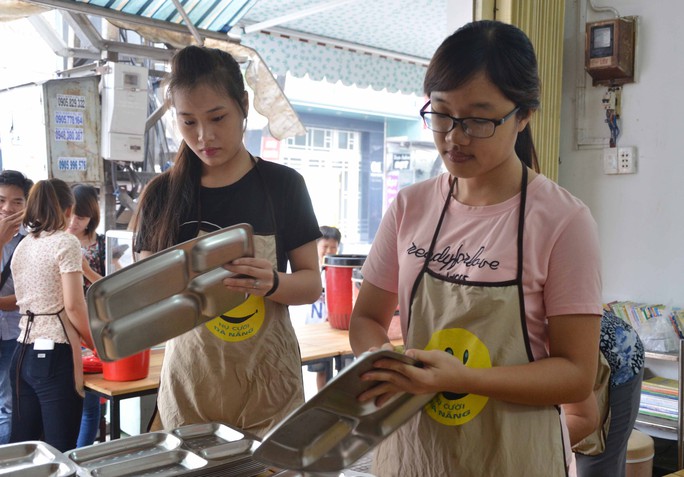 Các tình nguyện viên lau khay đựng cơm trước khi phục vụ cho người nghèo ở quán Nụ cười Đà Nẵng