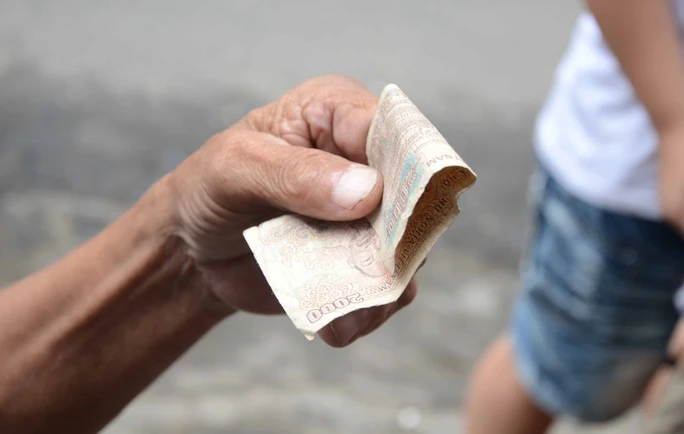 Tờ 2000 đồng của một thực khách được vuốt gọn gàng và thẳng nếp trước khi mua cơm