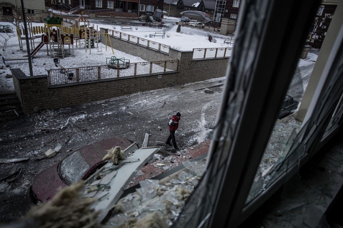 A Ukrainian man walks through the debris produced after the Ukrainian Army hit a building in Voroshilovsky area, center of Donetsk, Ukraine. Sunday, Jan. 18,...