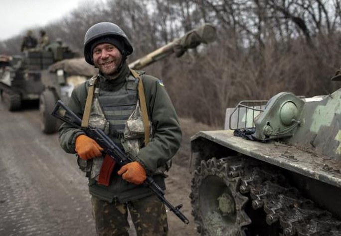A member of the Ukrainian armed forces and armoured personnel carriers smiles as they prepare to move to pull back from Debaltseve region, near Artemivsk February 26, 2015.   REUTERS-Gleb Garanich