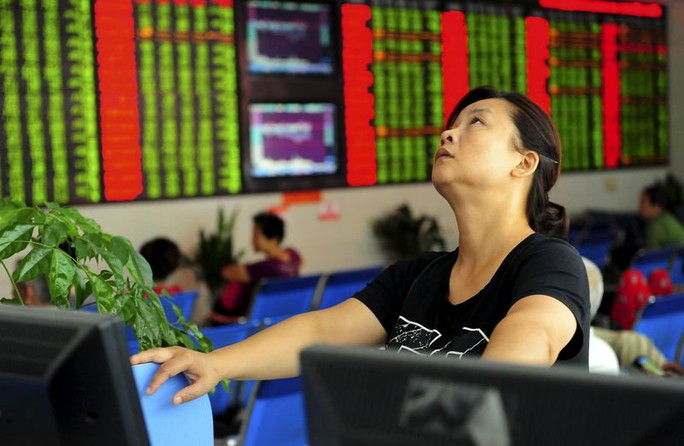 An investor looks up in front of an electronic board showing stock information at a brokerage house in Fuyang, Anhui province, China August 21, 2015. REUTERS/China Daily