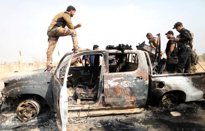 
Binh sĩ Iraq và chiếc xe của IS bị phá hủy gần Mosul. Ảnh: Reuters
