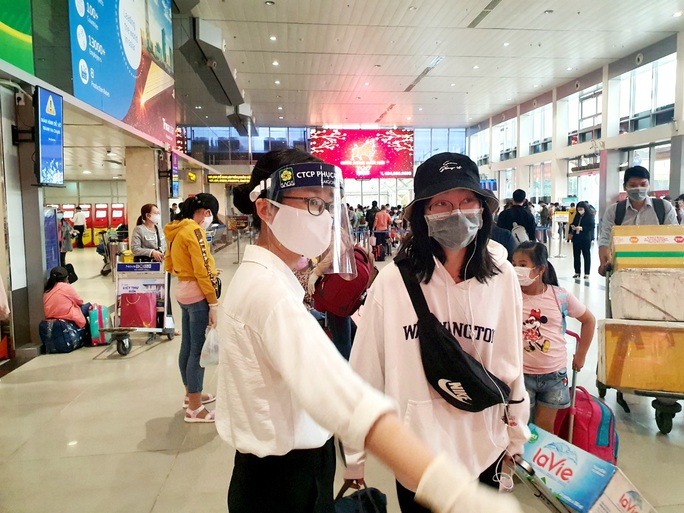 Sân bay Tân Sơn Nhất đông nghẹt ngày 25 Tết, nhiều khách trùm kín người để phòng dịch - Ảnh 1.