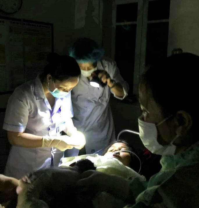 Các bác sĩ, hộ sinh rọi đèn pin đỡ đẻ cho sản phụ Hồ Thị Thái. (Ảnh: Trung tâm Y tế Hướng Hóa)