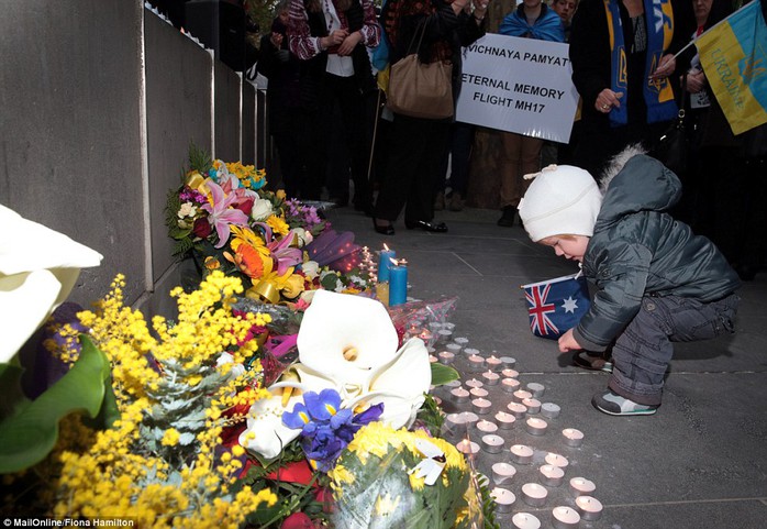 A young girl places a candle during a vigil for the attacks victims by the Victorian Society of Ukrainians on City Square in Melbourne 
