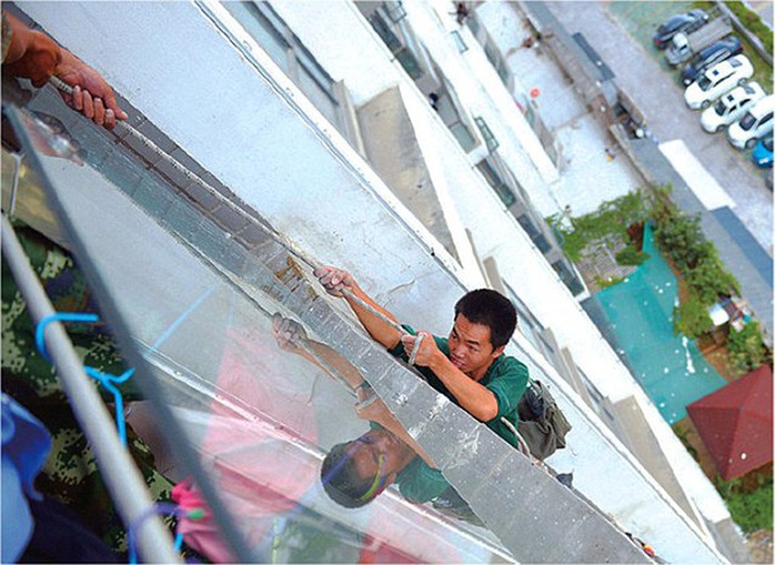 Hanging by a rope: Mr Liu was left dangling eight storeys above ground before he was rescued by firemen