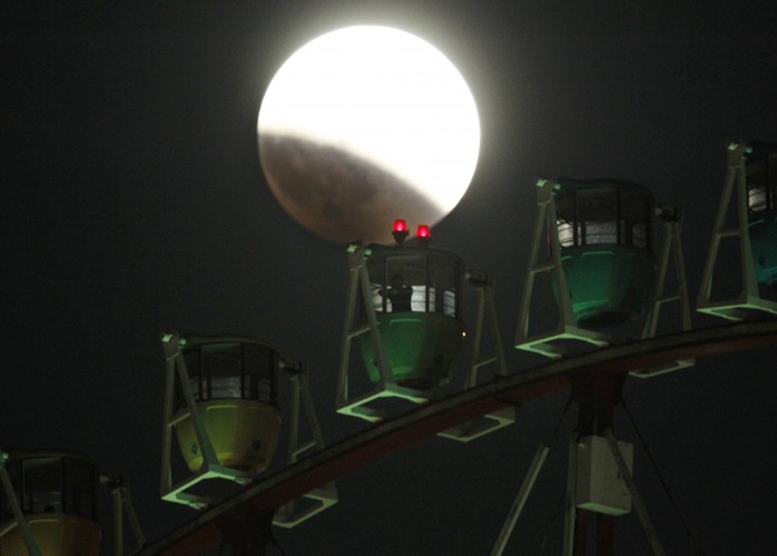 Bóng tối của trái đất đã xóa nhòa một phần của mặt trăng. Bức ảnh được chụp qua vòng quay Ferris ở Tokyo, Nhật Bản. Ảnh: Koji Sasahara/AP