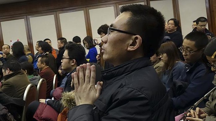 A relative of Chinese passengers aboard missing Malaysia Airlines Flight MH370 prays at a